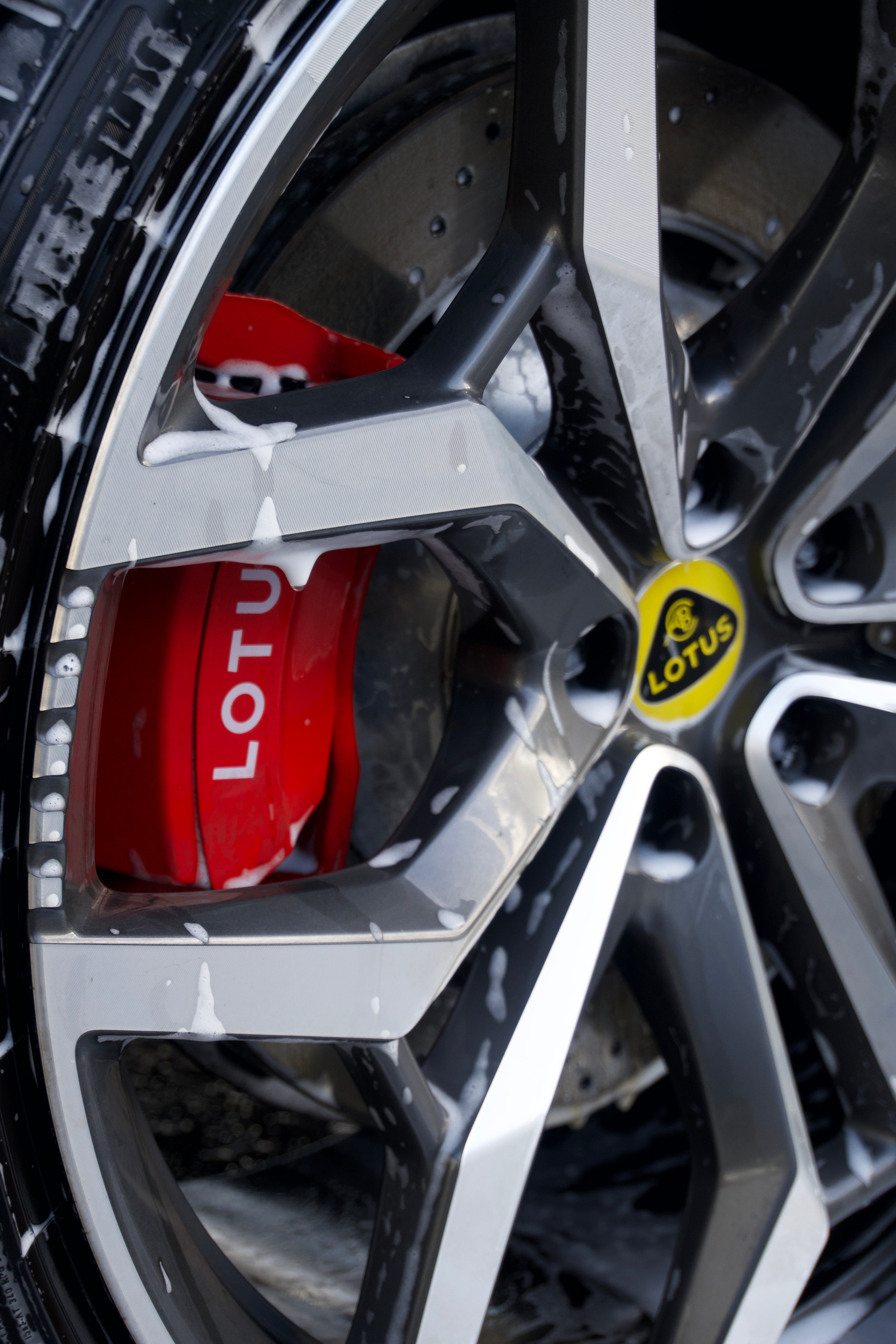 Close-up of a Lotus car wheel with red brake caliper and yellow Lotus logo.